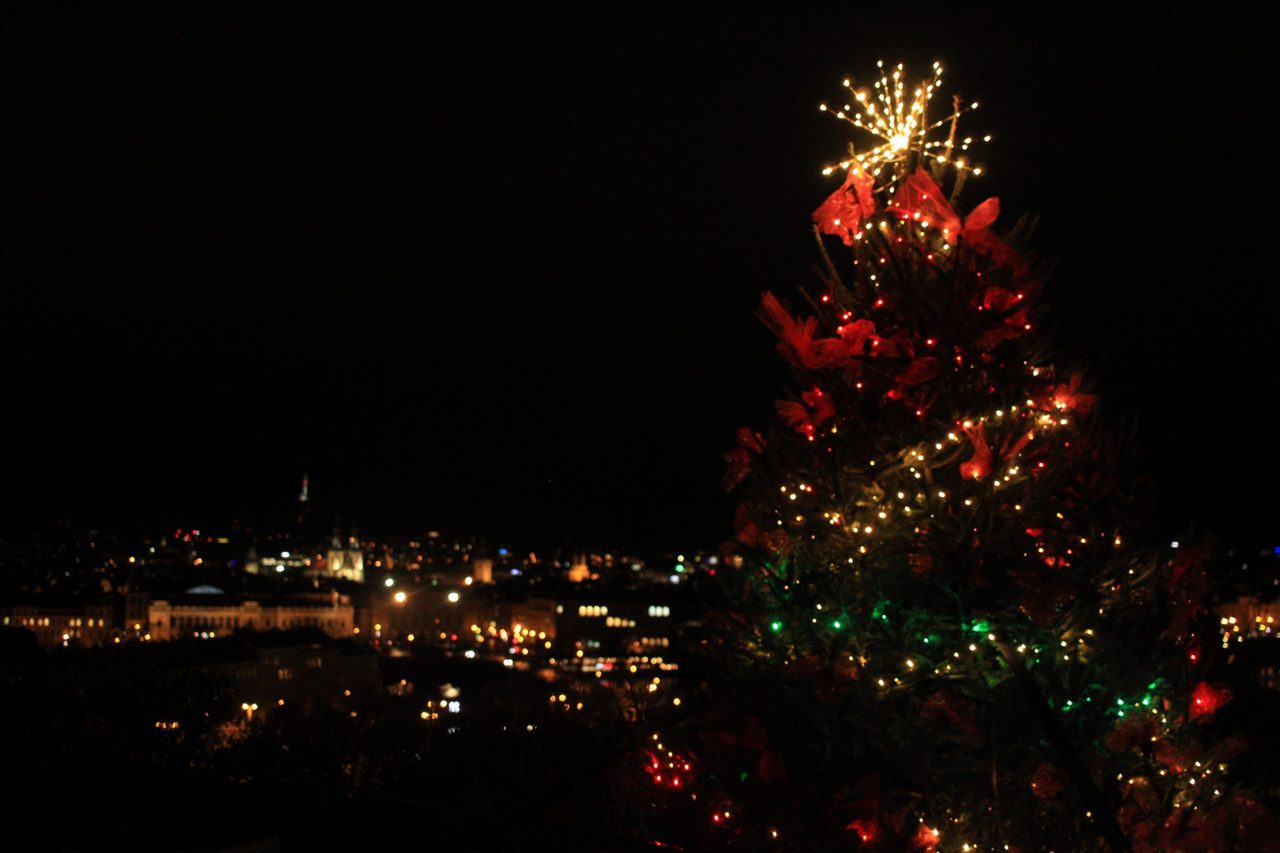 A lit Christmas tree glowing above the scattered city lights at night