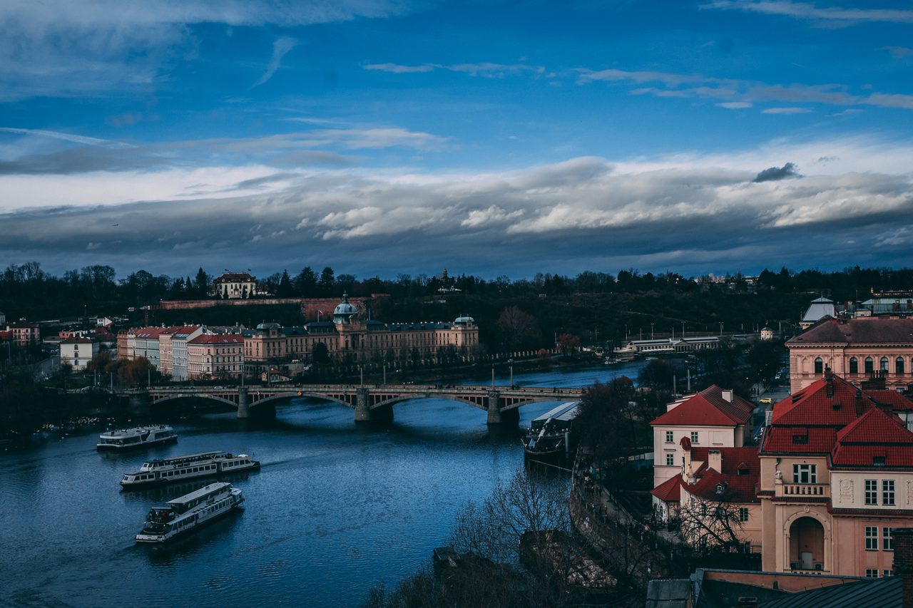 A bend of the Vltava with tourist boats and a low arched bridge