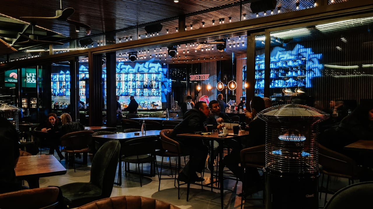 A restaurant glowing blue and amber on a winter night