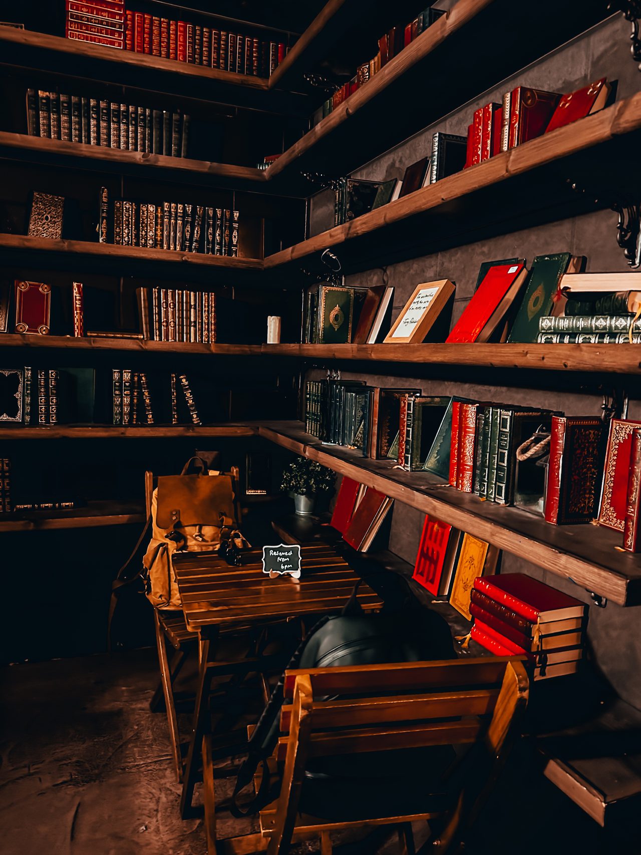 A dim vintage library of leather-bound books and a writing desk