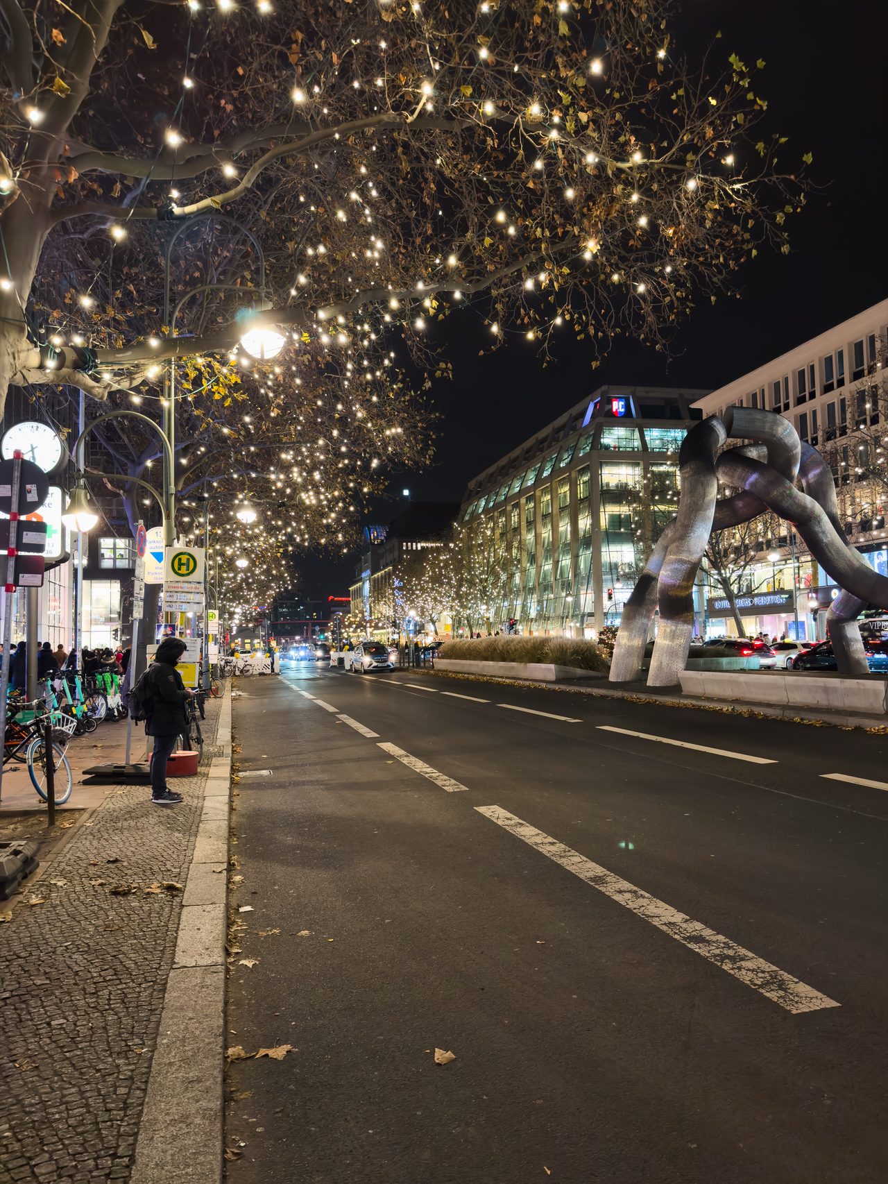 A Berlin boulevard at night, trees wrapped in fairy lights