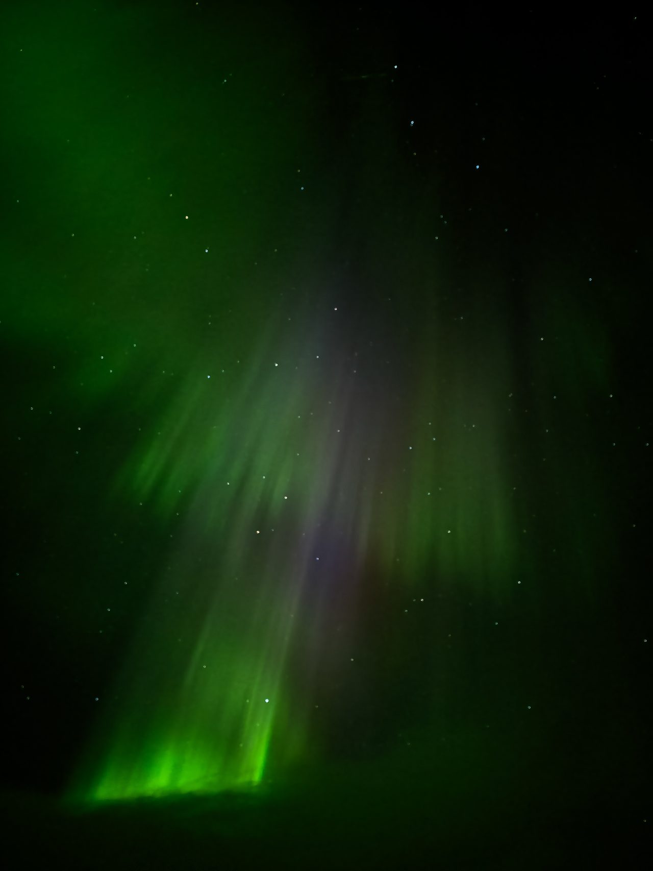 Green and violet aurora over a dark Icelandic sky