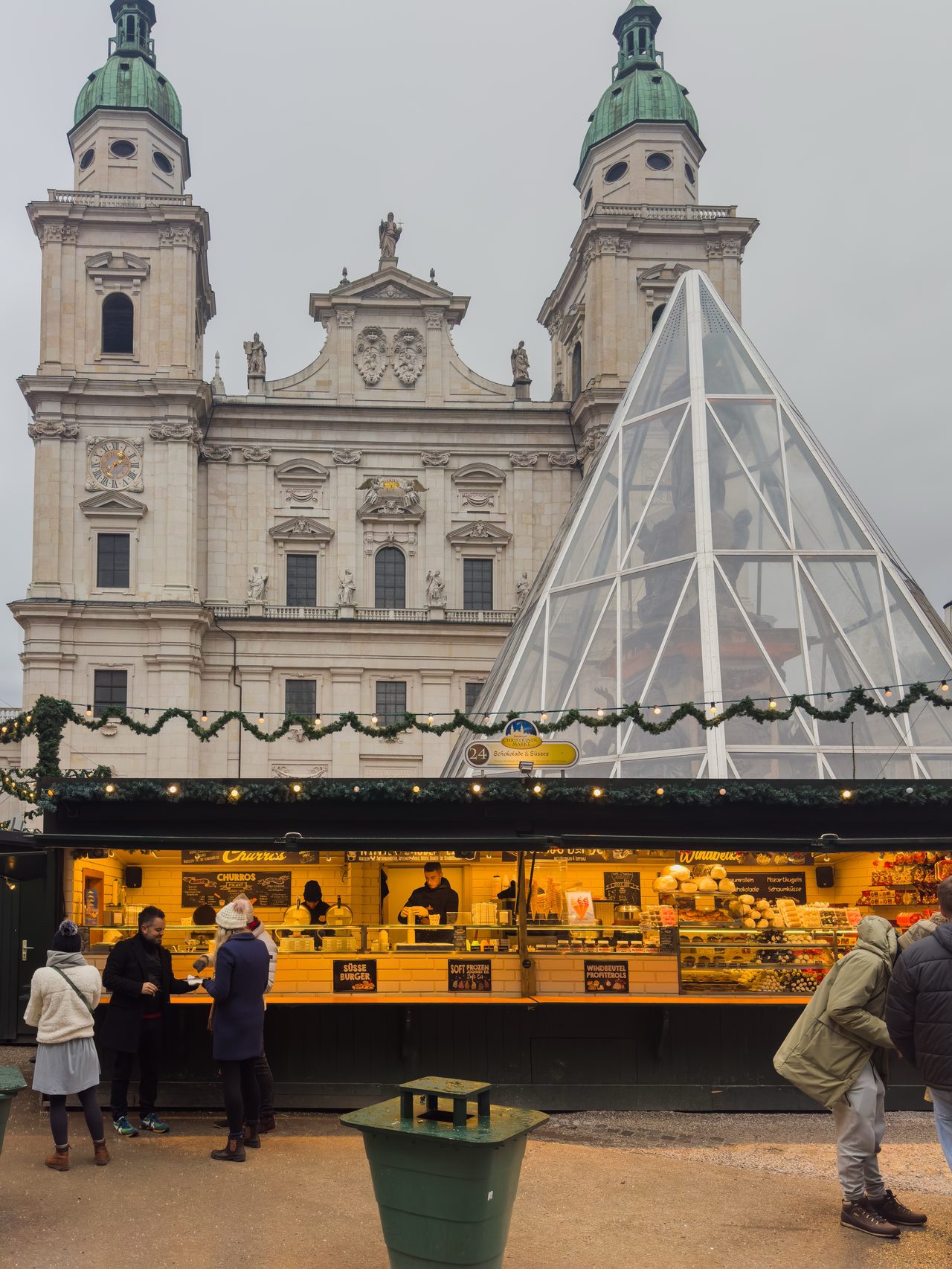 Christmas-market stalls and a glass pyramid before the illuminated cathedral
