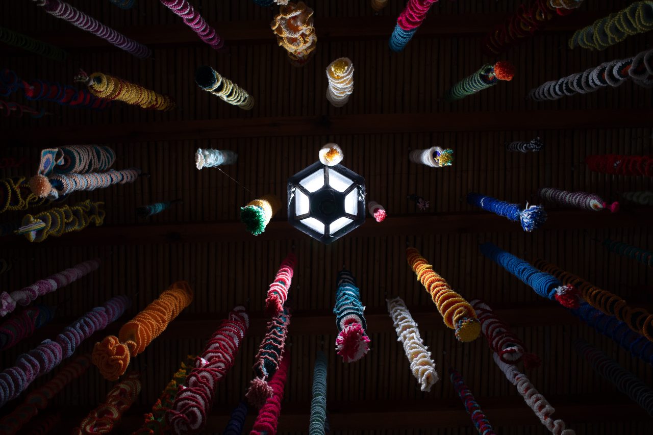Looking up at a hexagonal lantern ringed by colourful hanging ornaments